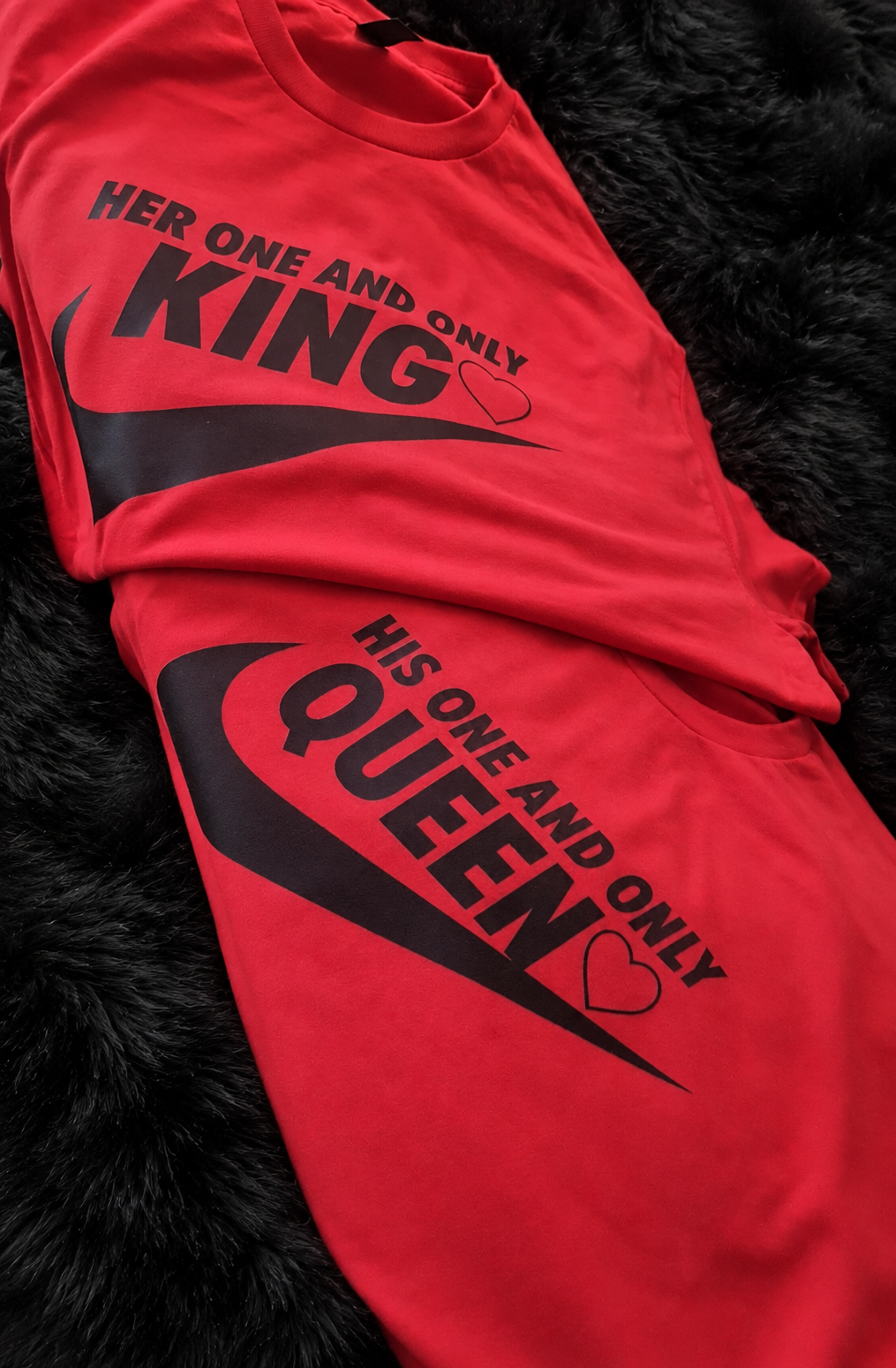 Matching red King and Queen couple shirts on a black plush rug